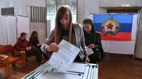 Uma menina vota em um referendo sobre a adesão da República Popular de Luhansk à Rússia em uma estação de votação.