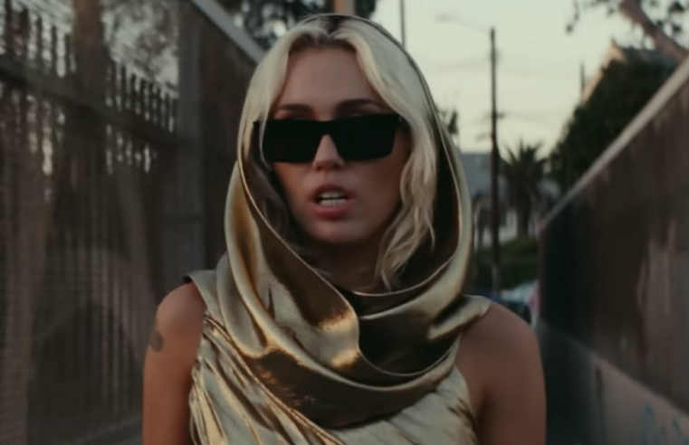 Miley Cyrus usa vestido dourado no videoclipe de “Flowers”